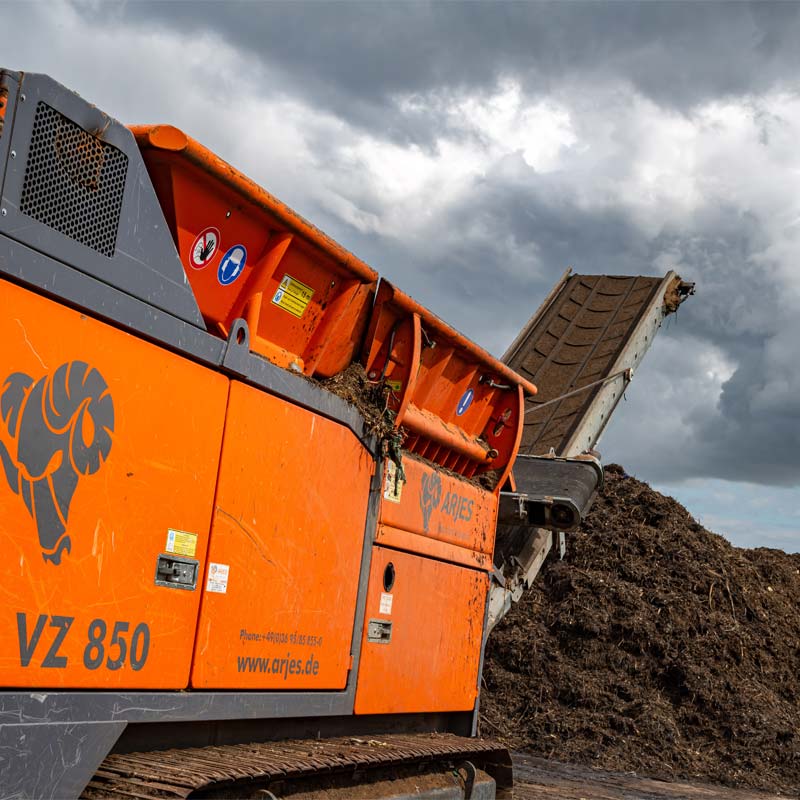 Digger tipping green waste